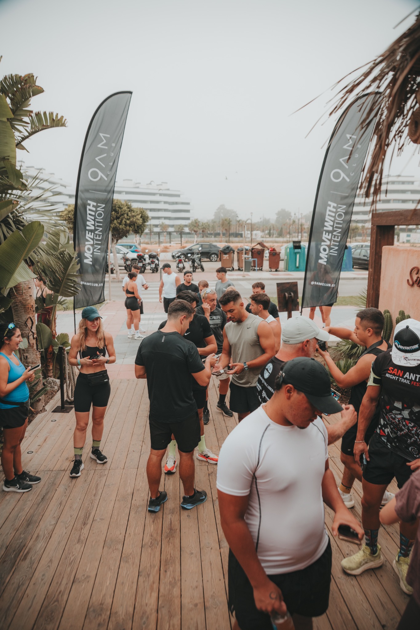Asistentes conversan a la entrada de un evento entre las banderas de 9AM